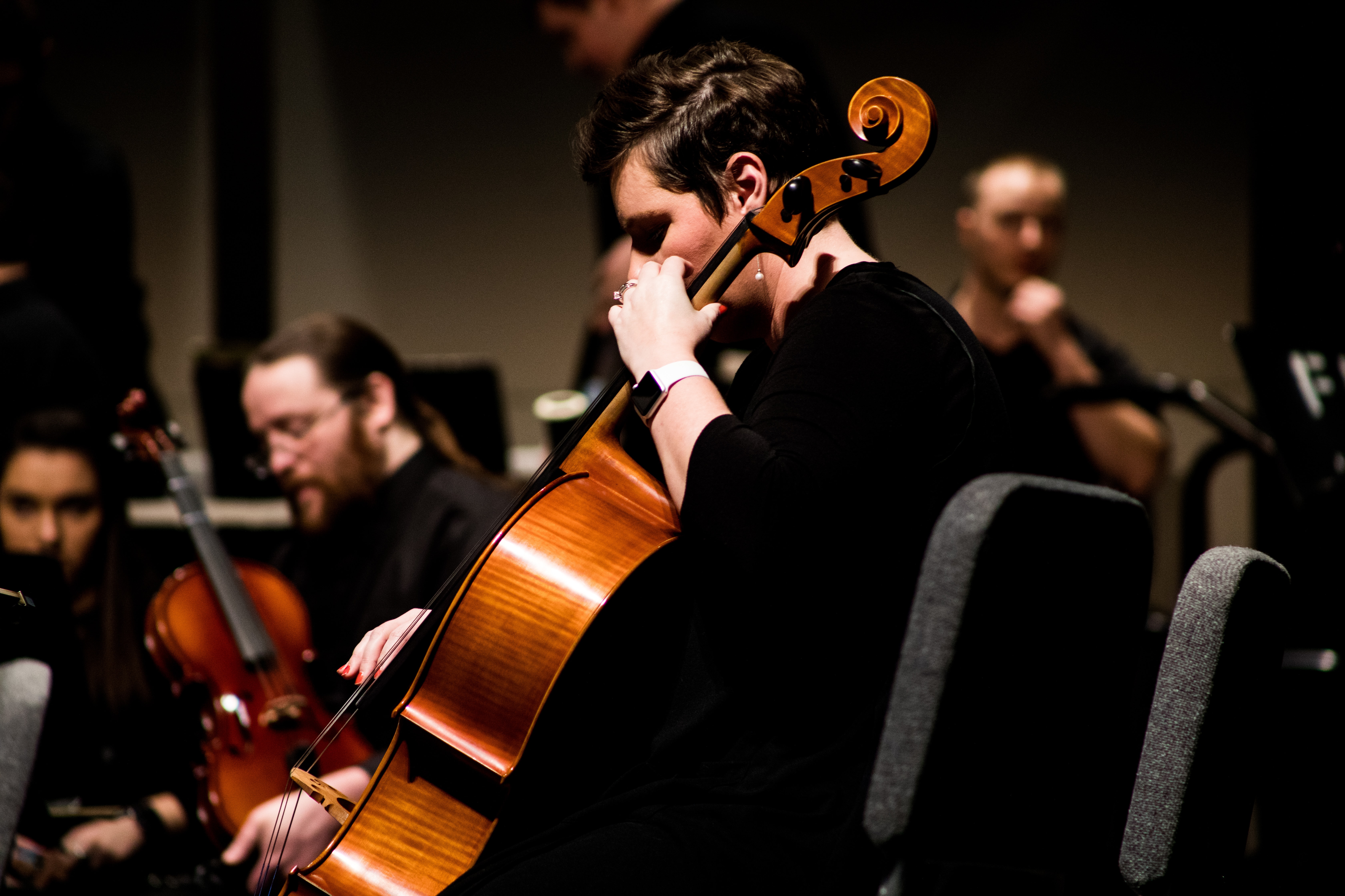 a man plays cello along with other strong musicians in a rehearsal space